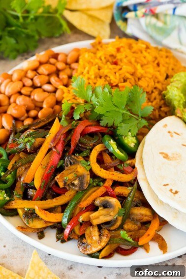 A platter of vegetarian fajitas served with rice and beans.