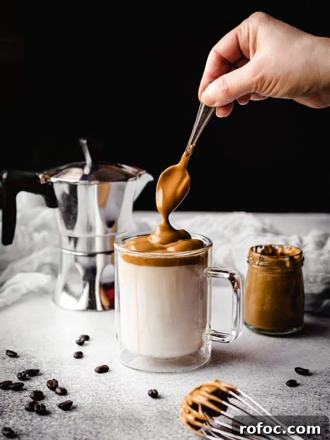 spooning a dollop of whipped coffee onto a mug of milk for dalgona coffee