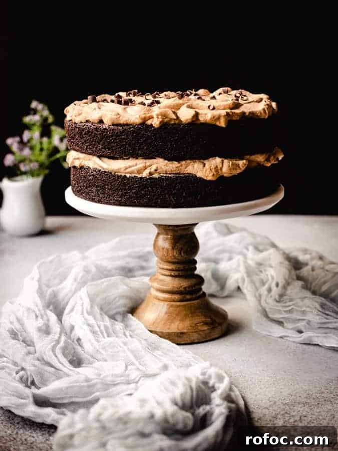 dalgona coffee chocolate cake on a cake stand with linen around and flowers behind