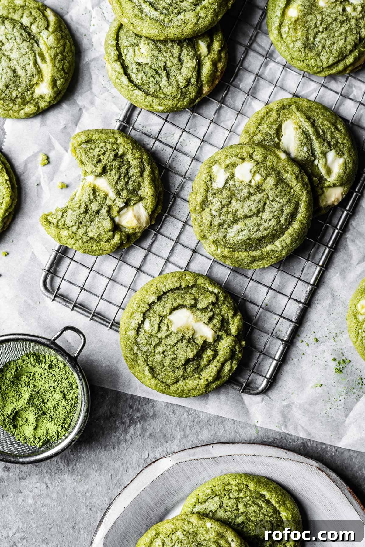 Green matcha white chocolate cookies on a cooling rack resting on white parchment paper.