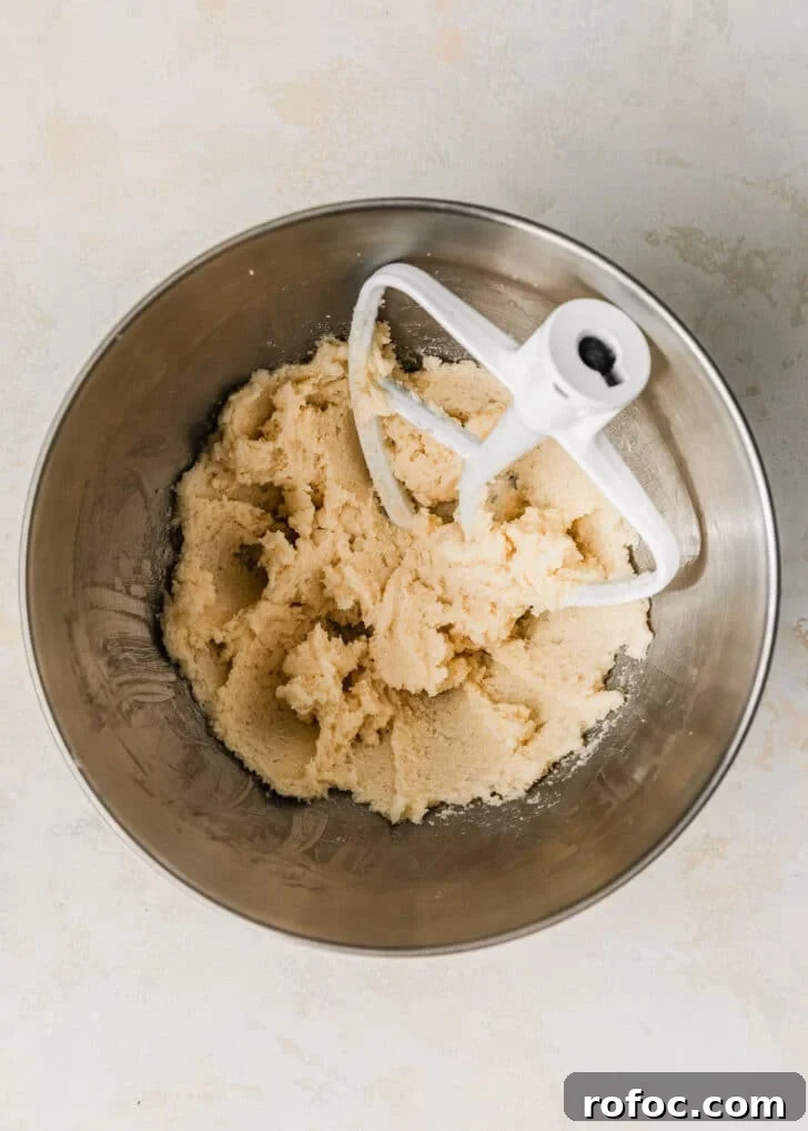 Mini Vanilla Cupcakes: Tender Bite-Sized Recipe 4 A silver bowl of creamed butter and sugar on a tan counter.