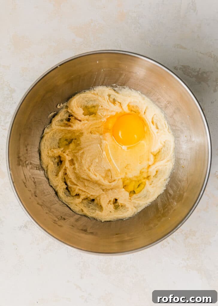 Mini Vanilla Cupcakes: Tender Bite-Sized Recipe 5 A silver bowl of butter, sugar, and eggs on a beige table.