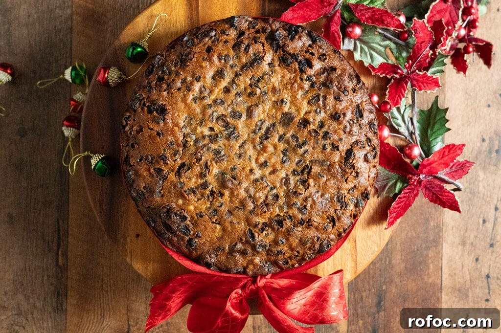Fruitcake on a wood platter with a red ribbon around it.