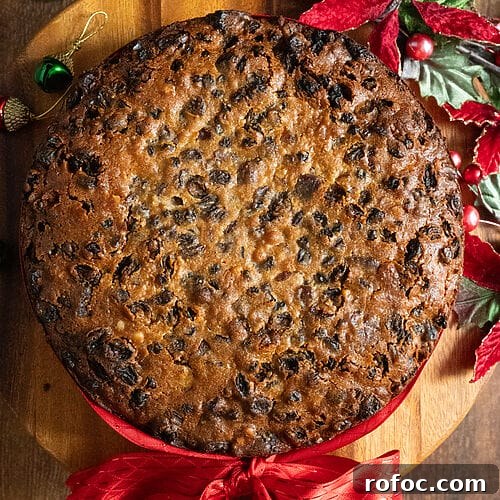 Fruitcake on a wood platter with a red ribbon around it.