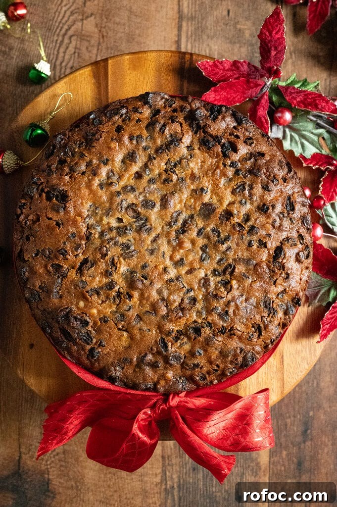 Fruitcake on a wood platter with a red ribbon around it.