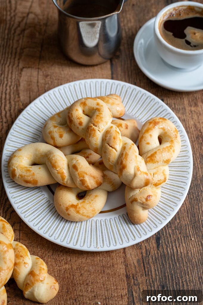 Greek butter koulourakia on a white plate with gold decor, next to a cup of Greek coffee.