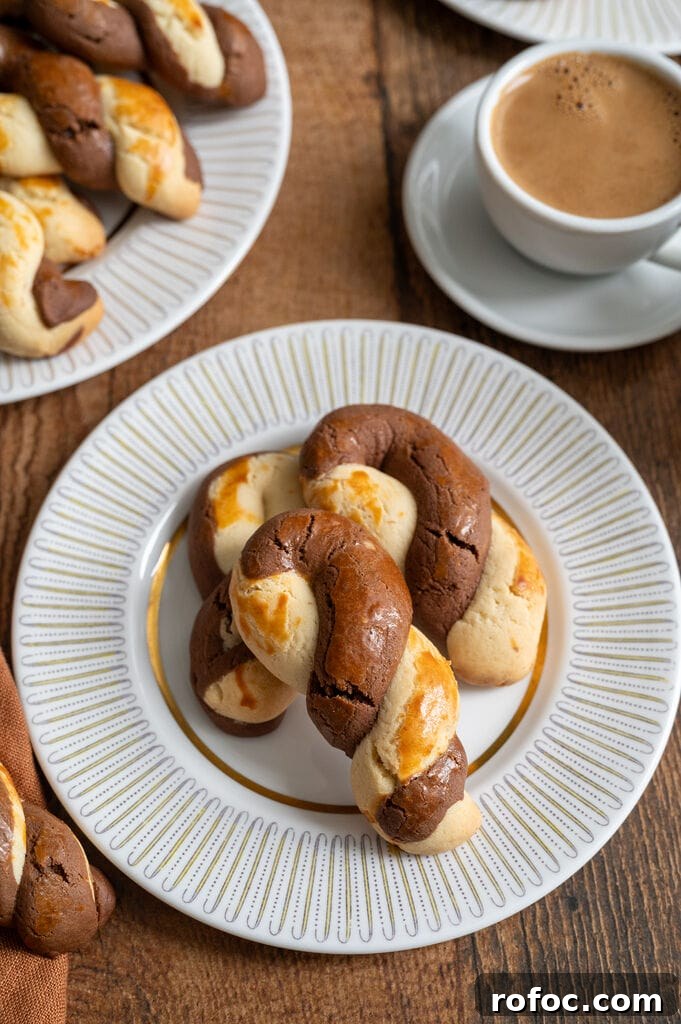 Greek butter koulourakia with a chocolate twist on a white plate with gold decor, and a cup of Greek coffee next to it.