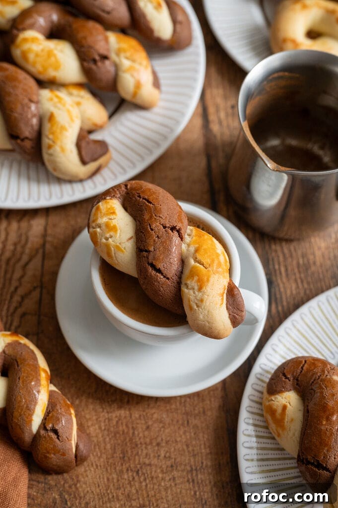 Greek butter koulourakia with a chocolate twist sitting on top of the cup of Greek coffee.