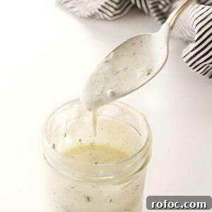Spoon drizzling creamy ranch dressing.