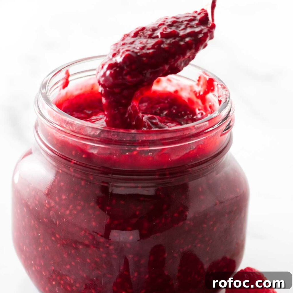 Spooning raspberry sauce out of a jar.