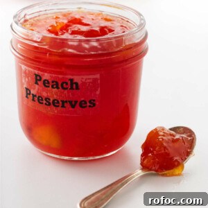 A spoon next to a jar of peach preserves.
