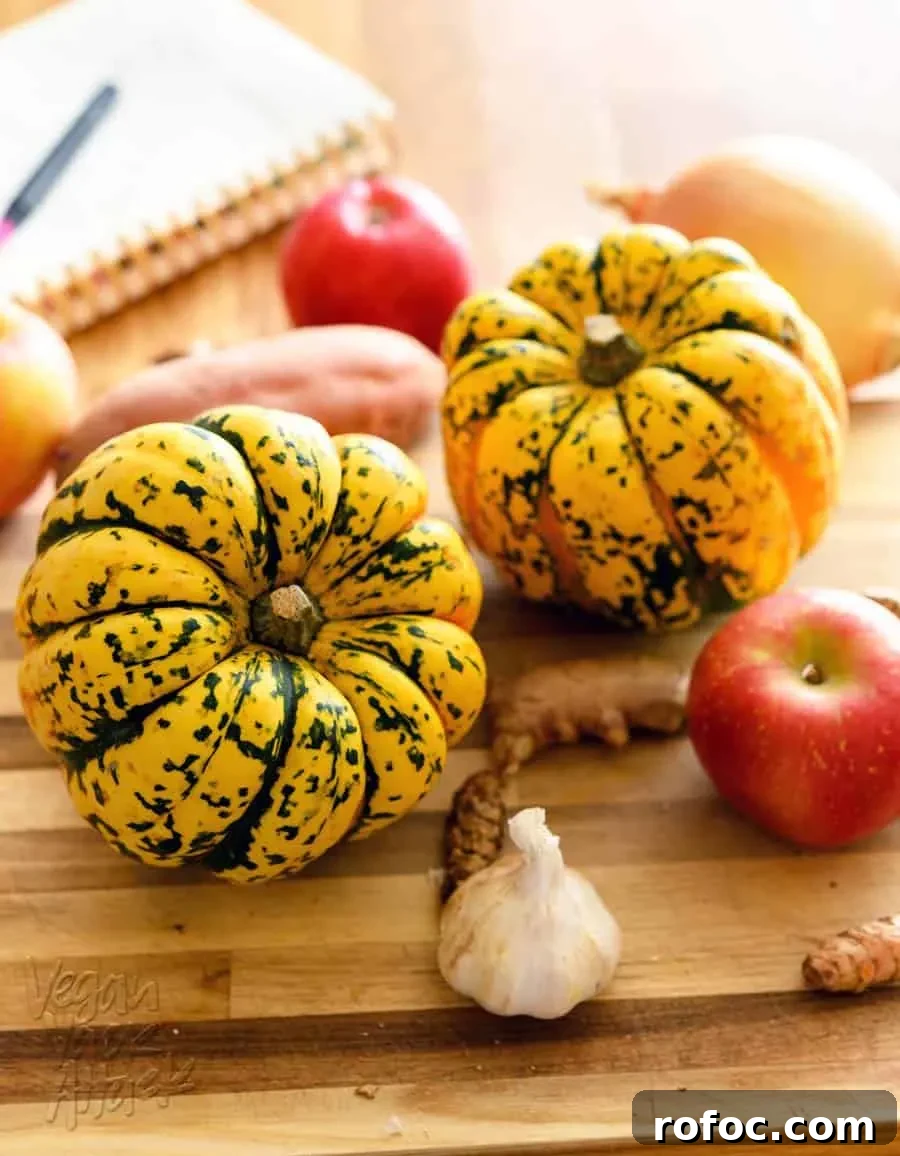 Vegan Winter Squash Recipes for Every Palate 3 two acorn squash on a cutting board with apples, turmeric, ginger, and garlic