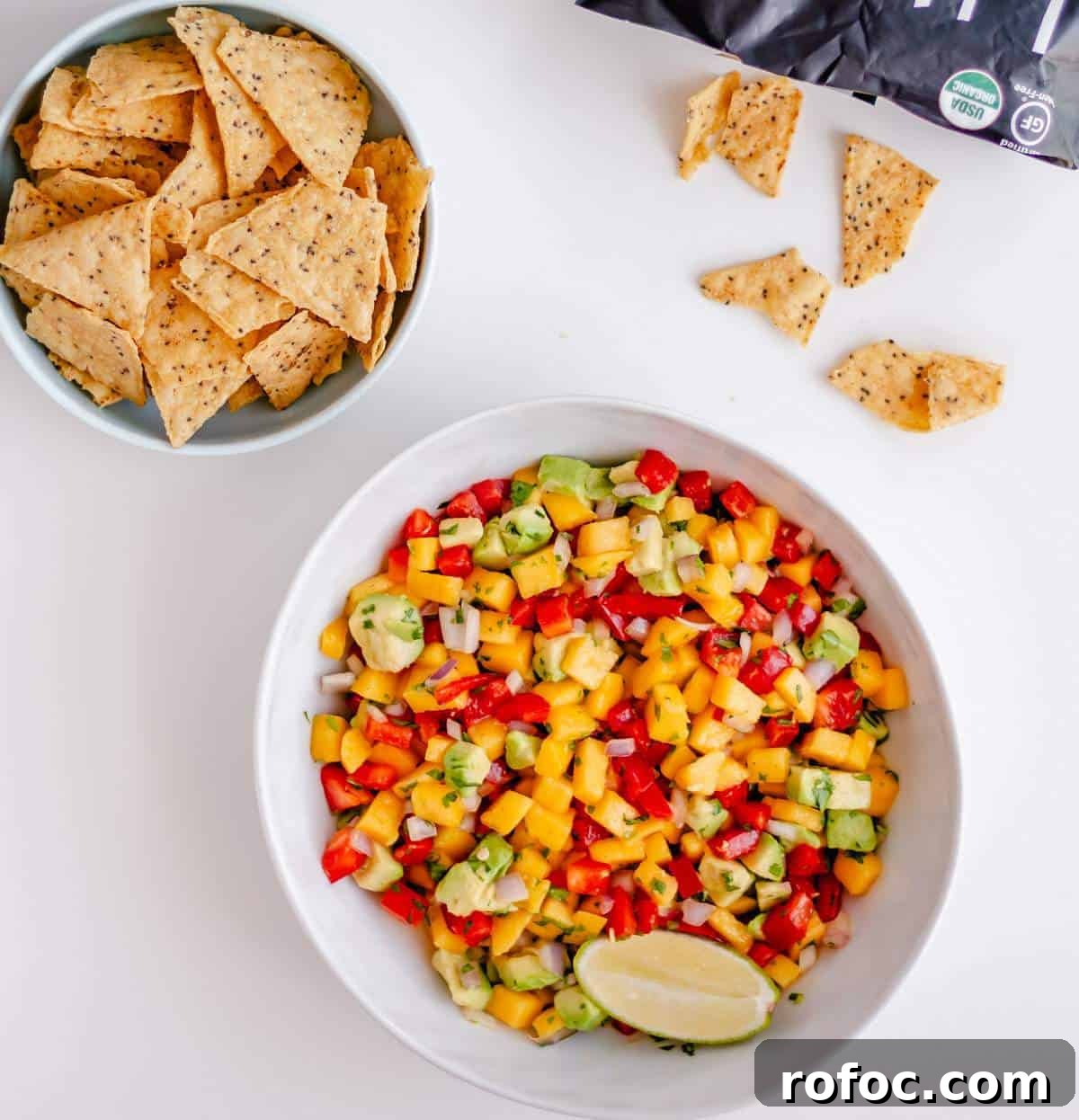 A bowl of homemade mango and avocado salsa and a bowl of chips.