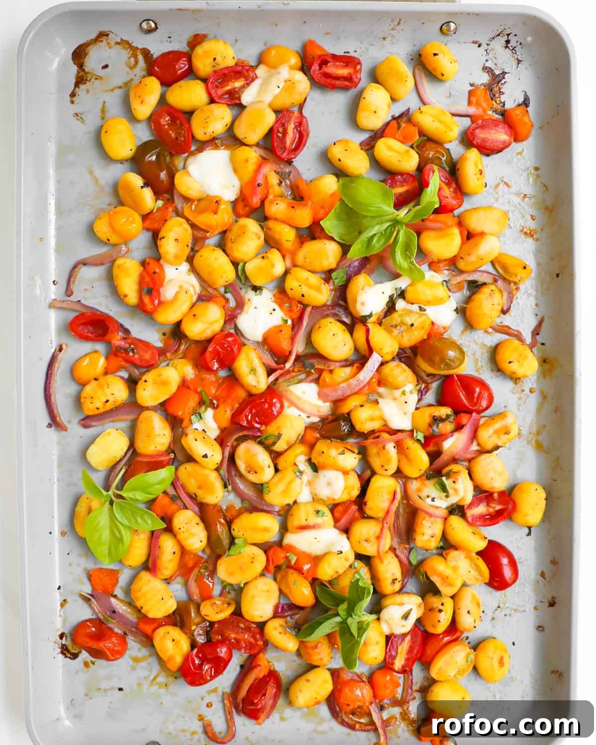 Crispy Sheet Pan Gnocchi with Roasted Vegetables 4 A pan of vegetables, gnocchi, and mozzarella with fresh basil on top.