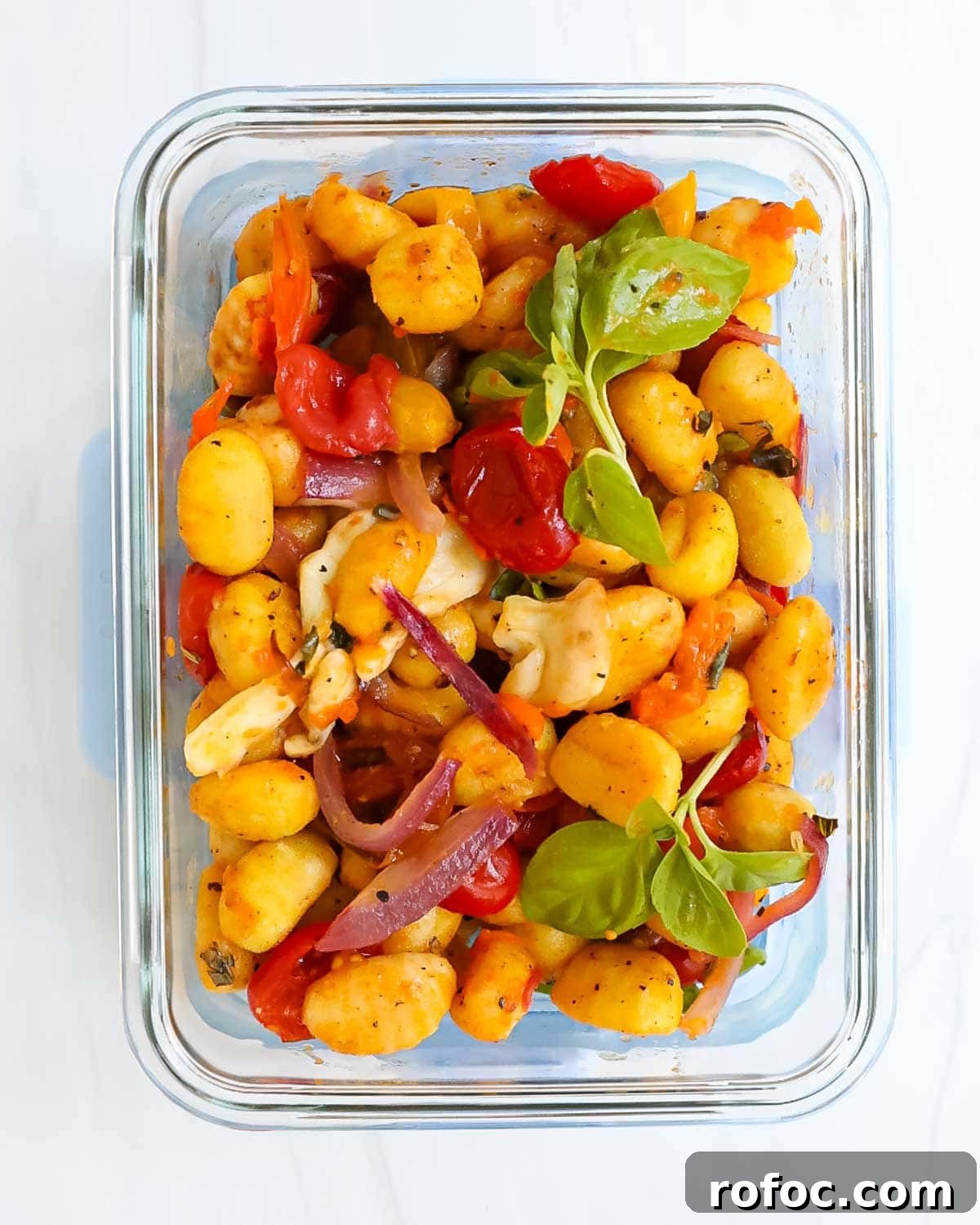 Crispy Sheet Pan Gnocchi with Roasted Vegetables 7 A clear glass meal prep container filled with gnocchi and vegetables.